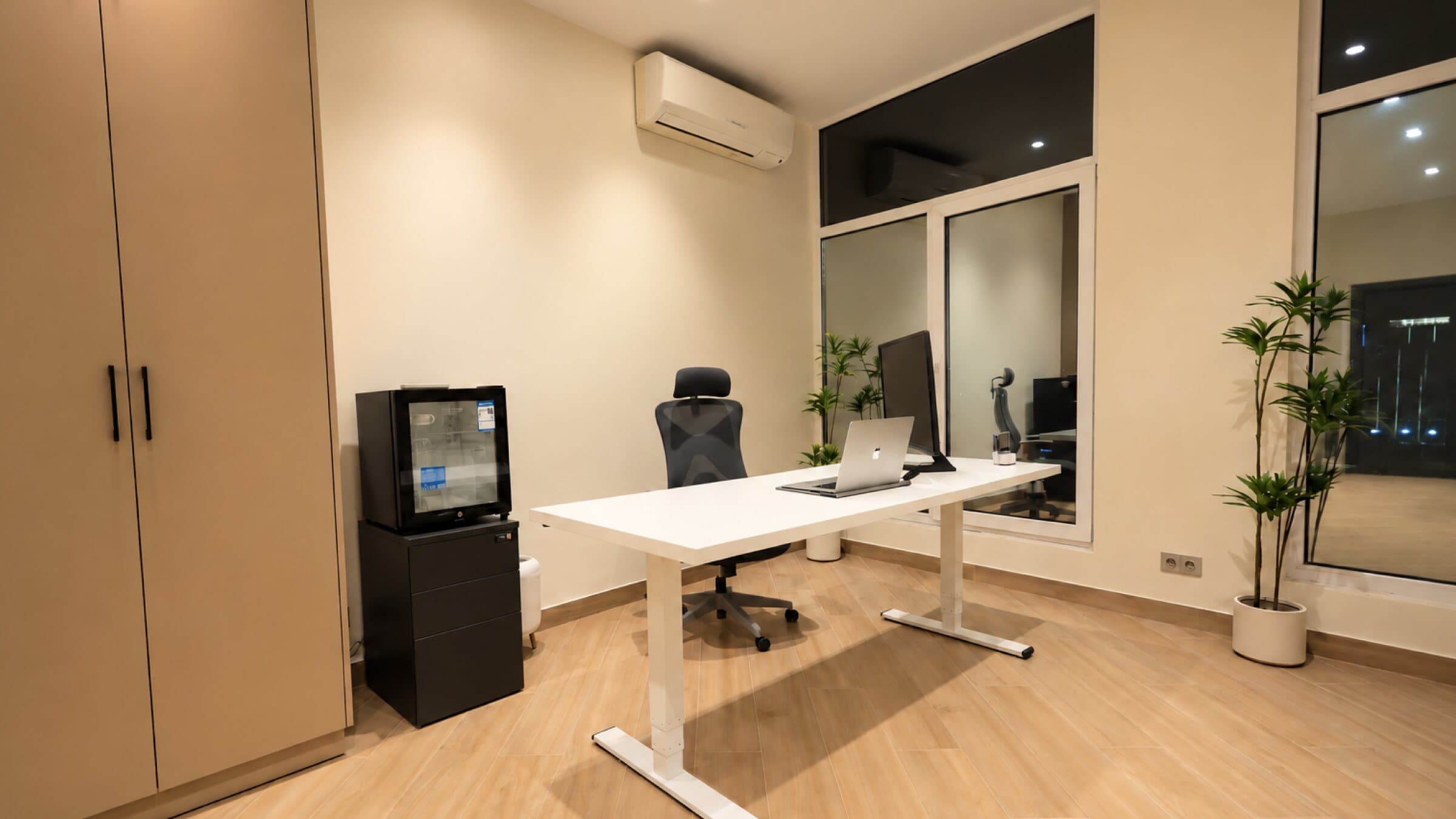 White desk by the window with a wardrobe and plants