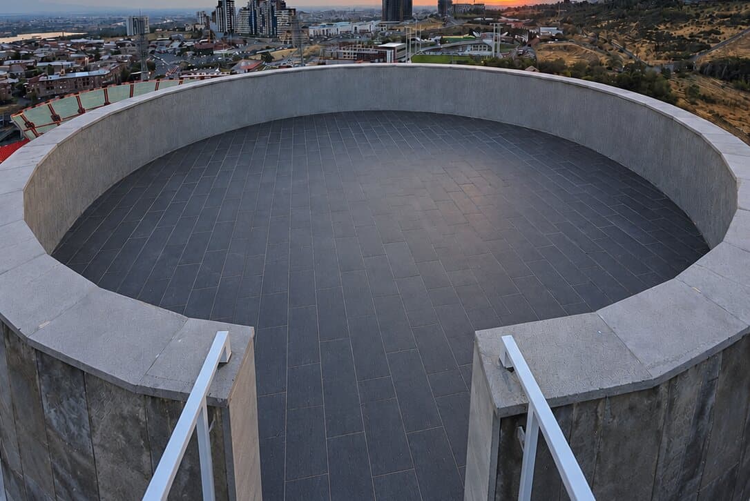 Steps up to the round rooftop platform with the city behind