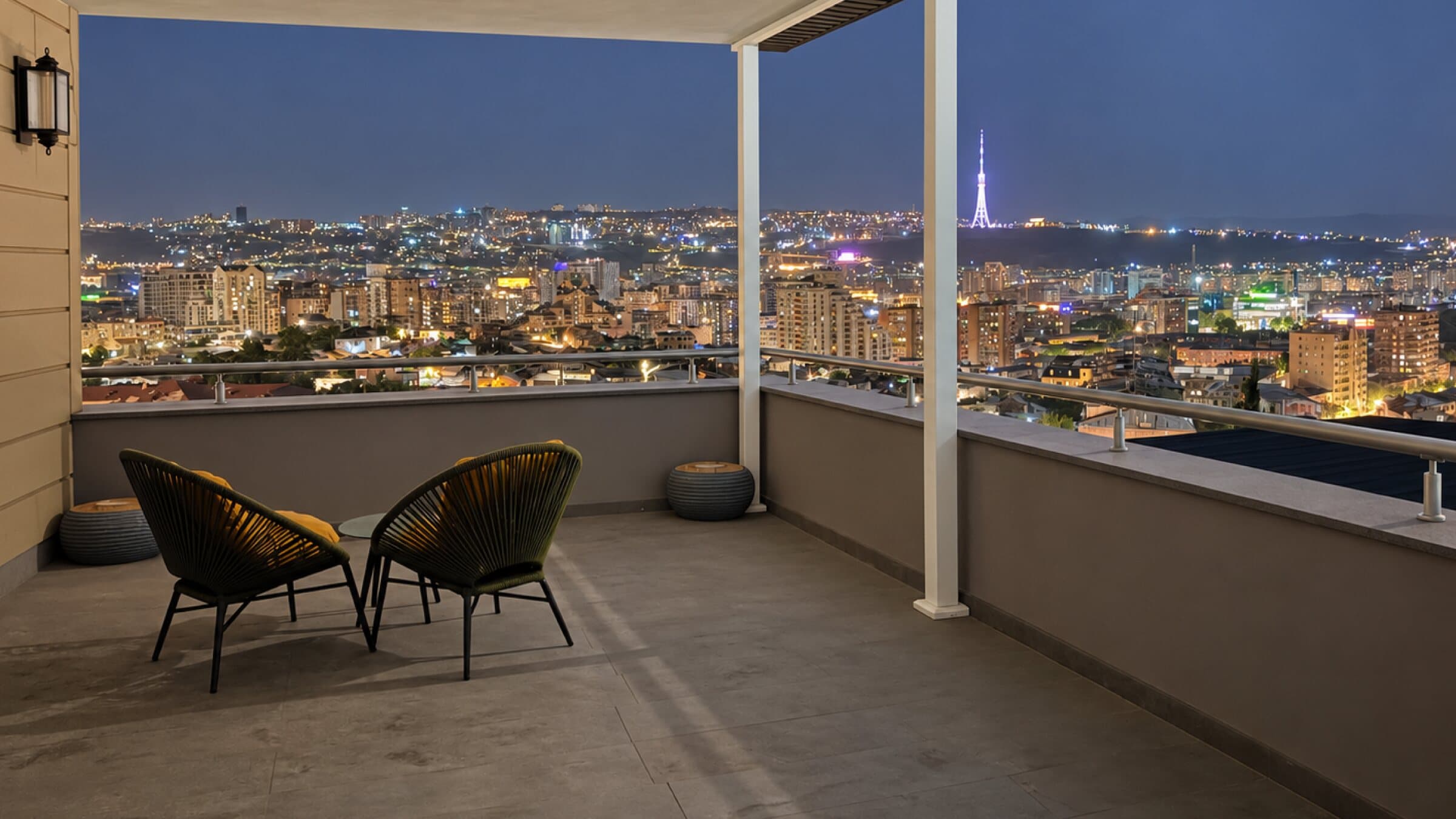 Terrace with armchairs overlooking the city lights at night