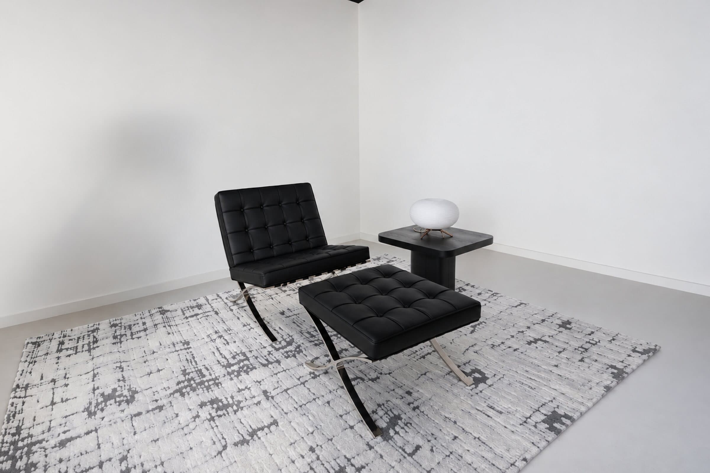 Black leather Barcelona chair and ottoman on a rug against the white cyclorama