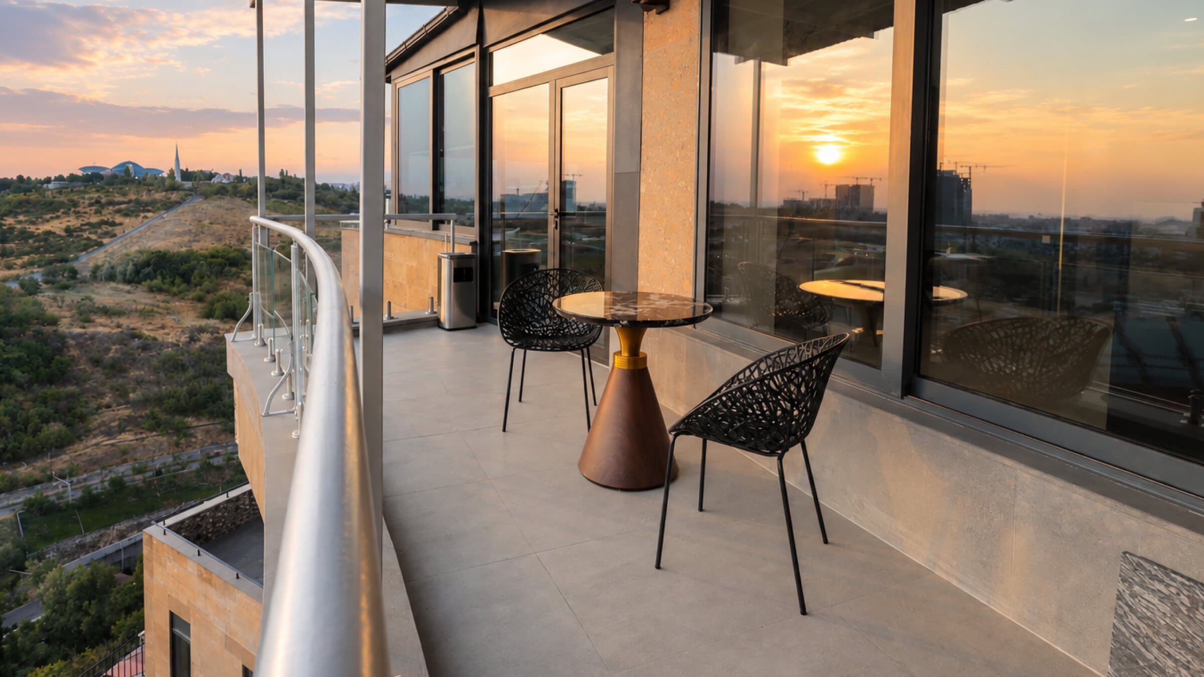 Balcony with a small table and a city view at sunset