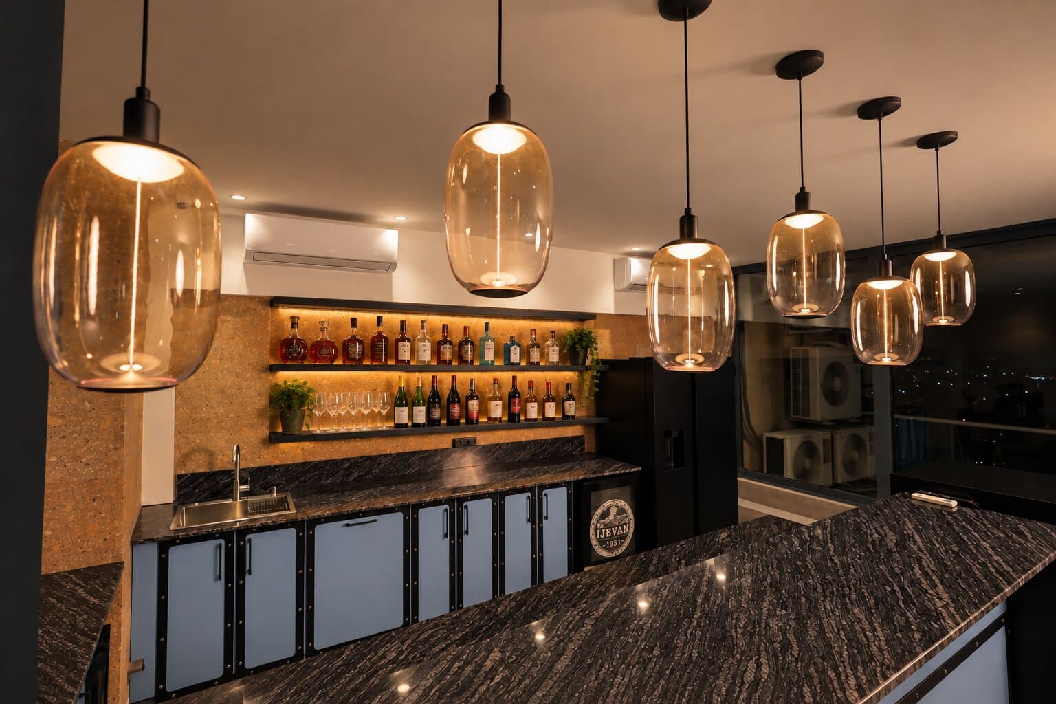 Marble bar counter with glass pendant lights and a lit bottle shelf